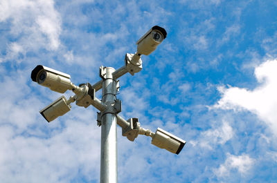 Low angle view of security cameras against blue sky