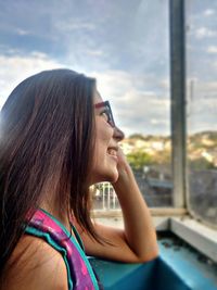 Side view of smiling teenage girl looking through window