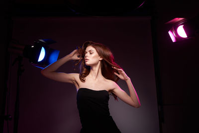 Portrait of young woman standing against wall