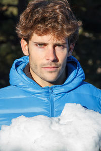 Portrait of young man holding snow standing outdoors