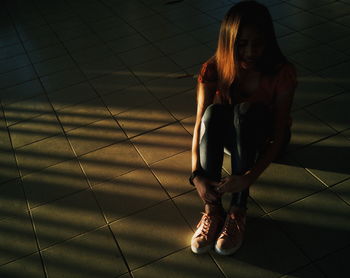 Full length of woman sitting on tiled floor