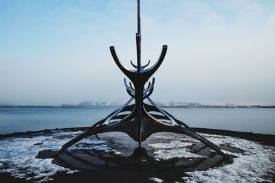 Close-up of snow on built structure against sea and sky