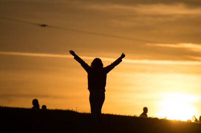 Silhouette of woman jumping at sunset