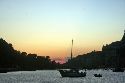 Sailboats moored on river against sky during sunset