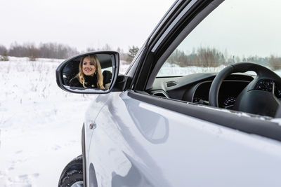 Reflection of woman in car side-view mirror