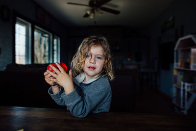 Young boy with long blond hair and blue eyes sitting at a table