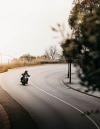 Horse riding motorcycle on road against sky