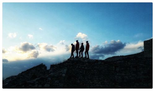 People standing on rock against sky