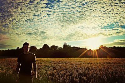 Scenic view of man in front of agricultural field against sky during sunset