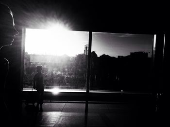 Silhouette man against sky seen through window