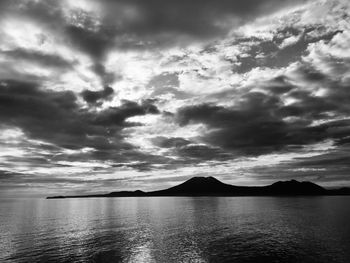 Scenic view of sea and mountains against dramatic sky