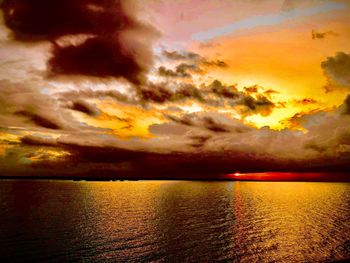 Scenic view of sea against dramatic sky during sunset