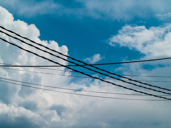 Low angle view of power lines against cloudy sky