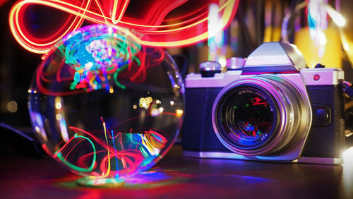 Close-up of camera and crystal ball on illuminated table