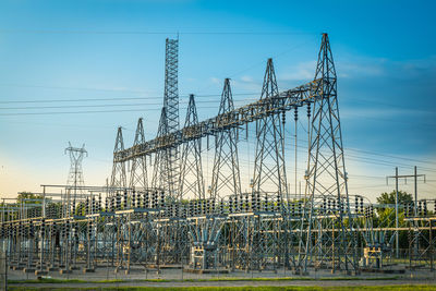 Electricity pylon by river against sky