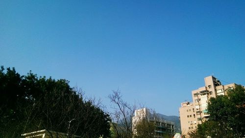 Low angle view of buildings against clear blue sky