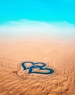 Heart shape on sand at beach against blue sky