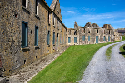 Old building by road against sky