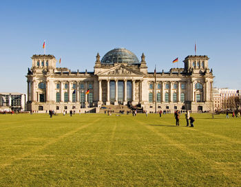 People in front of historical building against clear sky