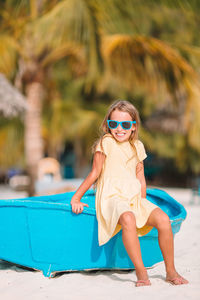 Portrait of girl wearing sunglasses sitting on swimming pool