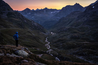 Rear view of man standing on mountain against sky