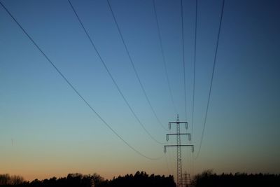 Silhouette electricity pylon against clear sky during sunset