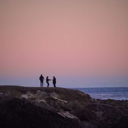 Silhouette people enjoying the beach against clear sky