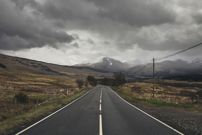 Country road against cloudy sky