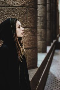 Side view of young woman standing against blurred background