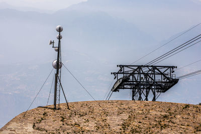 Electricity pylon on mountain against sky