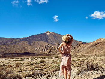 Midsection of woman standing on landscape against blue sky