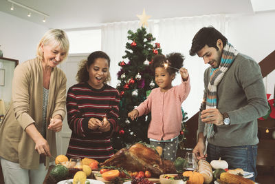 People holding illuminated sparklers while standing by food against christmas tree