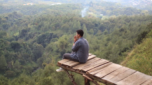 Man sitting on wood looking at mountain