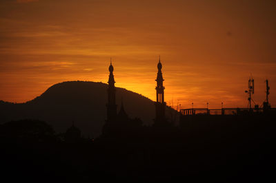 Silhouette of temple against building during sunset