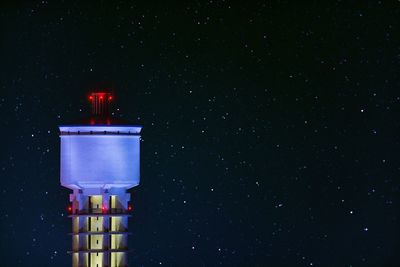 Illuminated water tank against star field at night