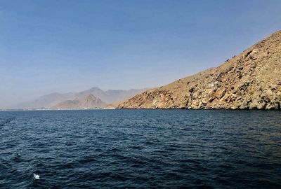 Scenic view of sea and mountains against clear blue sky