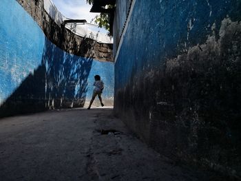 Child running on footpath amidst buildings