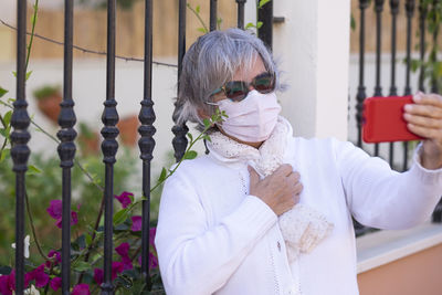 Senior woman wearing mask while taking selfie