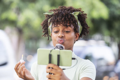 Young afro man recording a makeup tutorial to share on social networks.