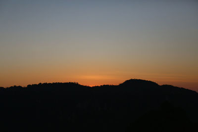 Scenic view of silhouette mountains against clear sky during sunset