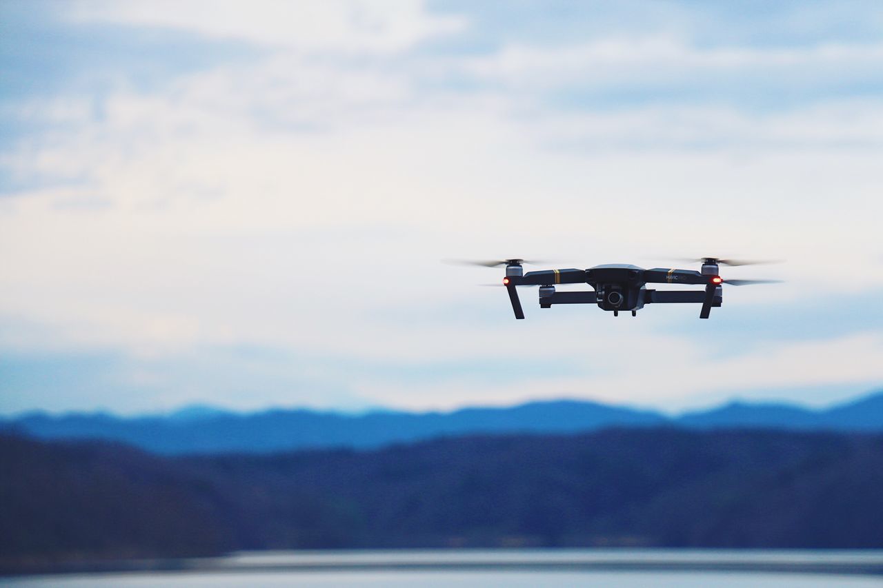 sky, transportation, flying, mode of transport, mid-air, cloud - sky, air vehicle, mountain, mountain range, day, scenics, outdoors, no people, nature, landscape, airplane, technology, close-up, drone