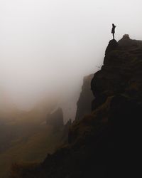 Silhouette woman on mountain against sky during foggy weather