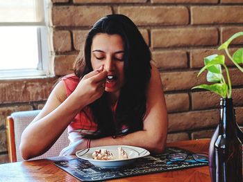 Young woman eating food on table at restaurant
