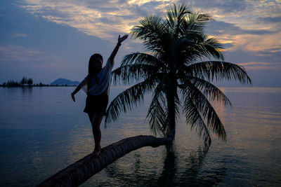 Young woman standing at beach during sunset