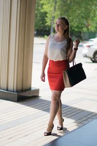 Full length of woman walking on footpath in city