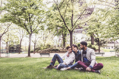 Friends sitting on grassy field at public park