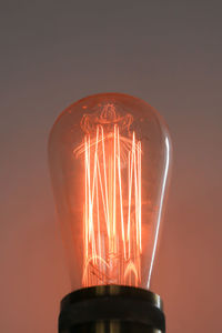 Close-up of illuminated light bulb against gray background