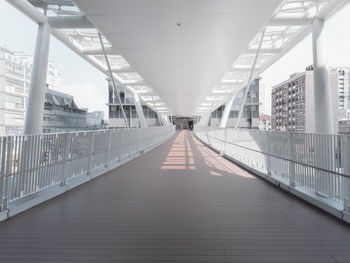 Empty footbridge amidst buildings