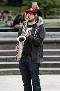 Midsection of man holding camera while standing outdoors