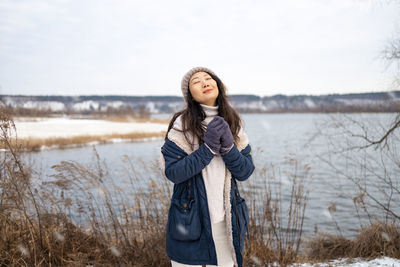 Portrait of young woman standing against lake